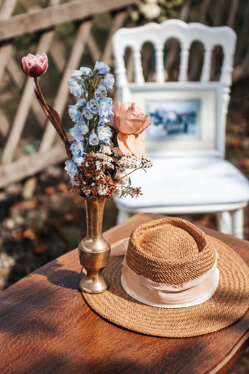 Vase ancien fleuri et chapeau de paille disposés sur une table en bois